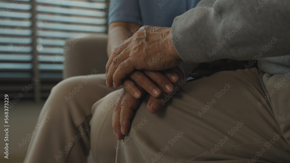 Close-up hand of senior woman comforting as holds hand of elderly man