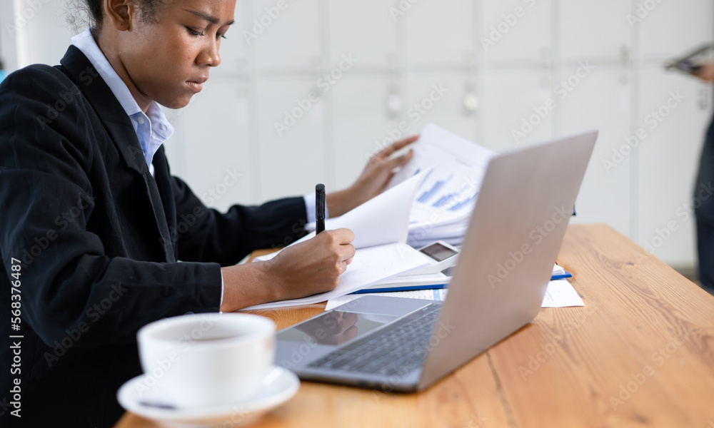 Young African American businesswoman working on laptop with documents and stressed over worked from work in the office, Overworked woman concept. Young African American businesswoman working on laptop with documents and stressed over worked from work in the office, Overworked woman concept.