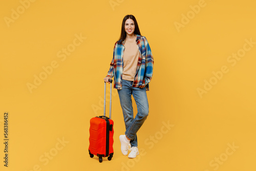 Full body smiling traveler fun woman wear casual clothes hold valise isolated on plain yellow background studio. Tourist travel abroad in free spare time rest getaway. Air flight trip journey concept.