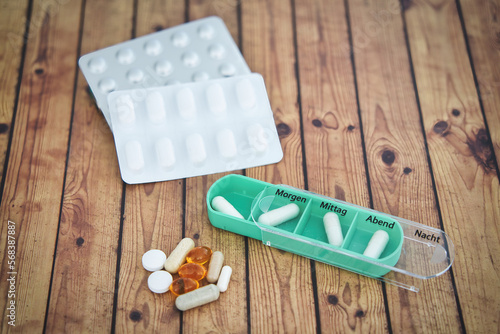 Bilde på lerret Daily green drug dose - pills organized in a pill box, german letters means mond