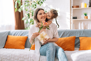 Daughter hugged her mother and gave a gift and flowers. mother's day