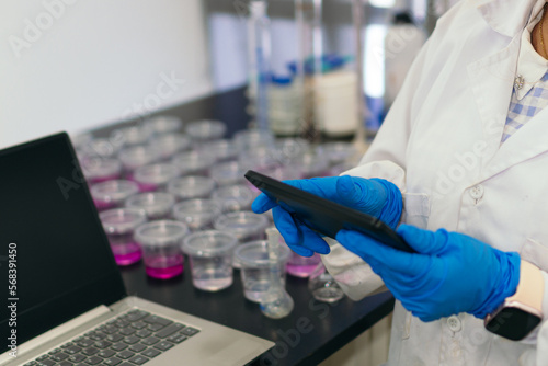 Unrecognizable woman in laboratory typing on a tablet