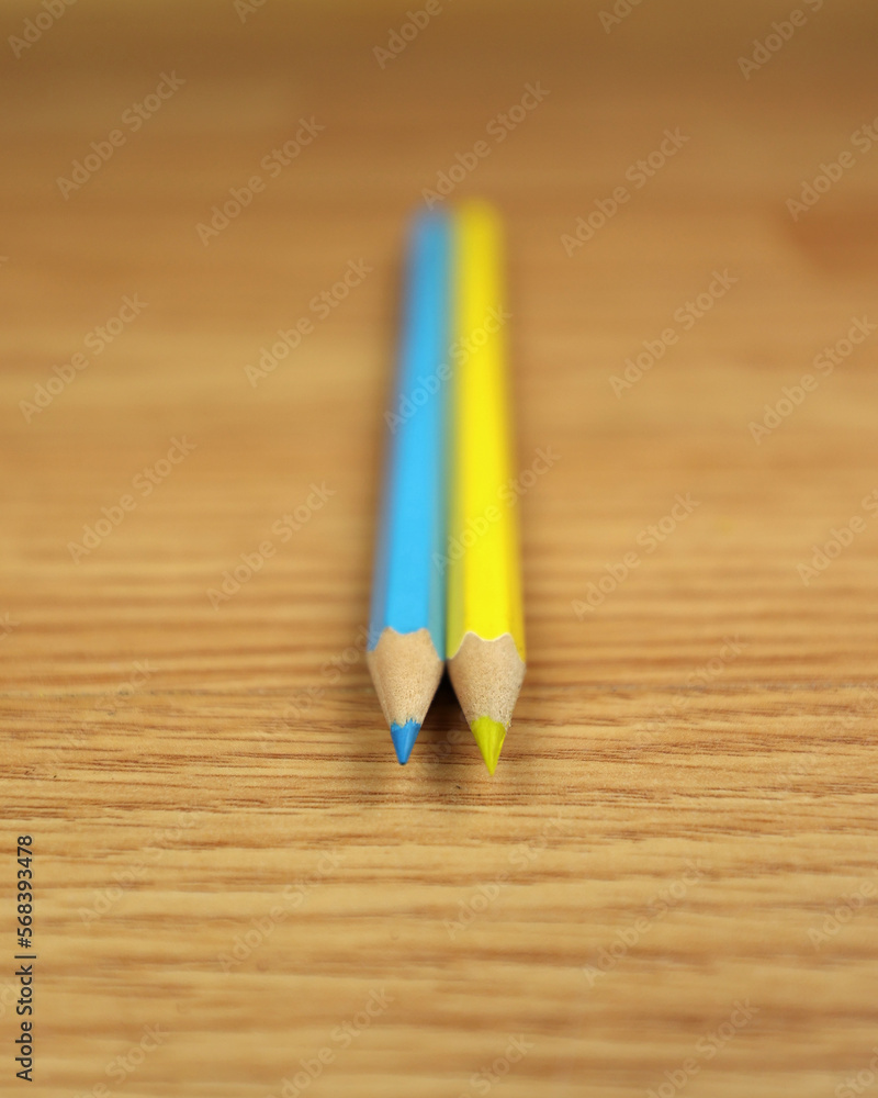 Obraz premium Two blue-yellow pencils on a wooden background, like the flag of Ukraine. Preparation for study