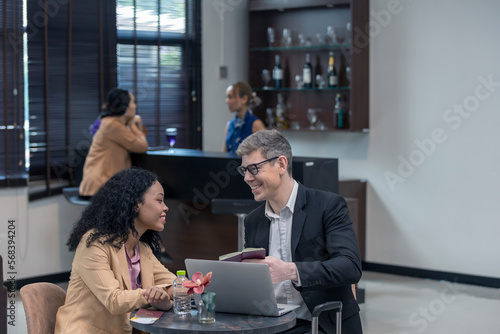 Two business workers are waiting and taking facility service at an exclusive airline lounge. Travelers get refreshment at a private lobby to be ready for their trip.