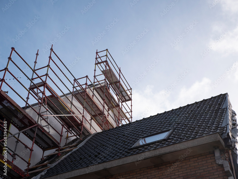 Scaffolding on and next to the roof of an adjacent house to be able to work on the roof of a new building Scaffolding on and next to the roof of an adjacent house to be able to work on the roof of a new building