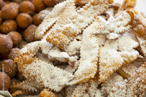 Frappe or chiacchiere and onbaked castagnole typical Italian carnival fritters dusted with powdered sugar. Biscuits with sugar for the carnival of Venice. Traditional sweet pastries of the carnival  photo
