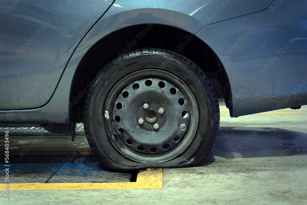 Car with a punctured and broken wheel in a car repair shop