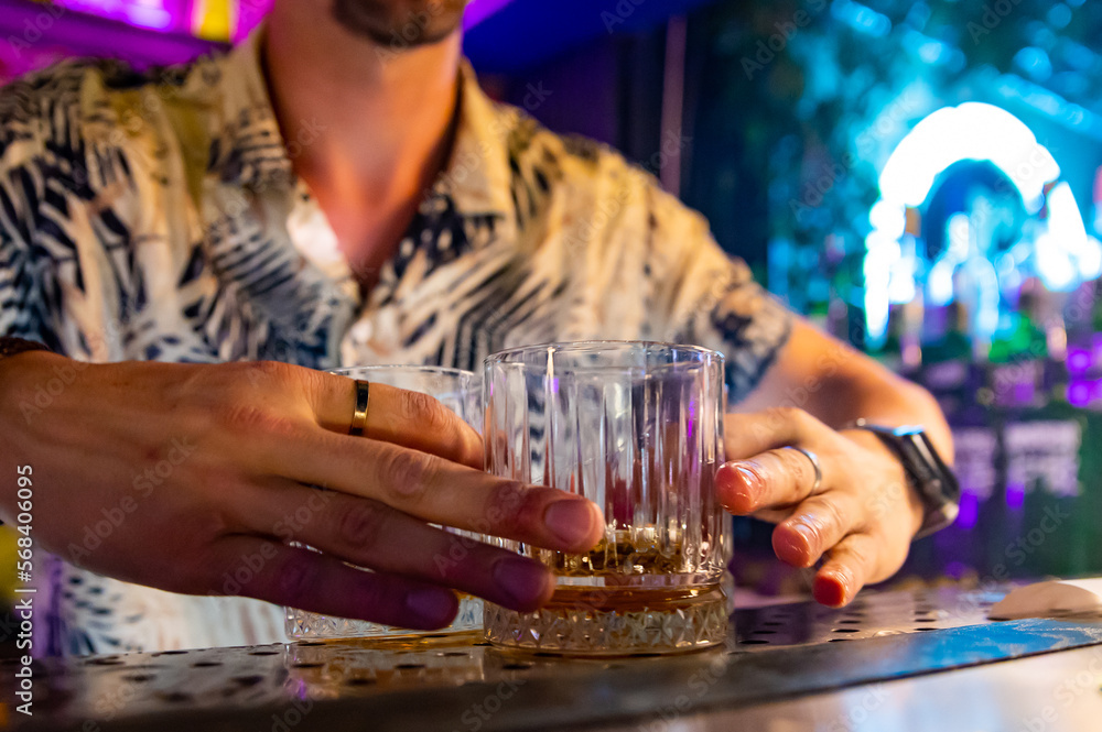 Bartender hand pouring whiskey on glass in bar