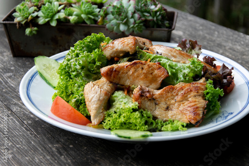 Typical Bavarian salad of turkey, vegetables and herbs on a wooden background, soft selective focus