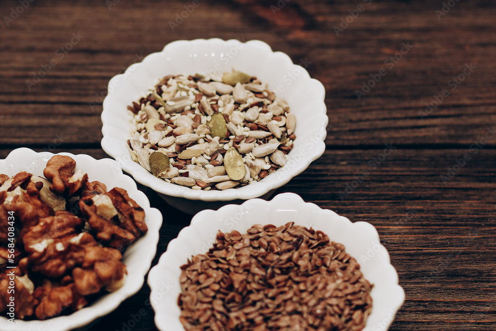 A mixture of sunflower, pumpkin and flax seeds with nuts in a bowl on a wooden table. A mixture of sunflower, pumpkin and flax seeds with nuts in a bowl on a wooden table.