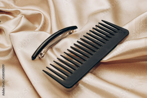 Elegant black hair clip and comb on a silk golden background.
