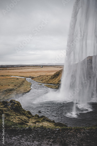 Waterfall road landscape in Iceland with wild mountains and meadows background