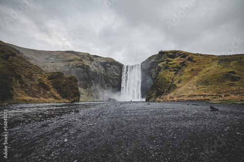 Iceland landscape with waterfall in the background and black colored earth with grayish sky