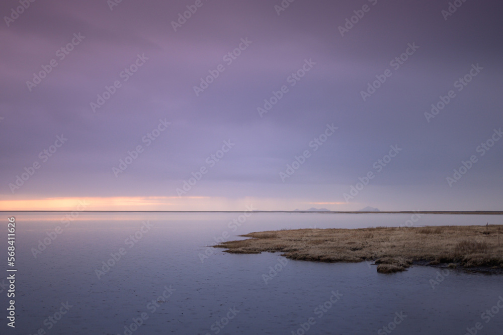 Fototapeta premium Tranquil landscape on a lake in Iceland at sunset with a mountain in the background and bluish tones