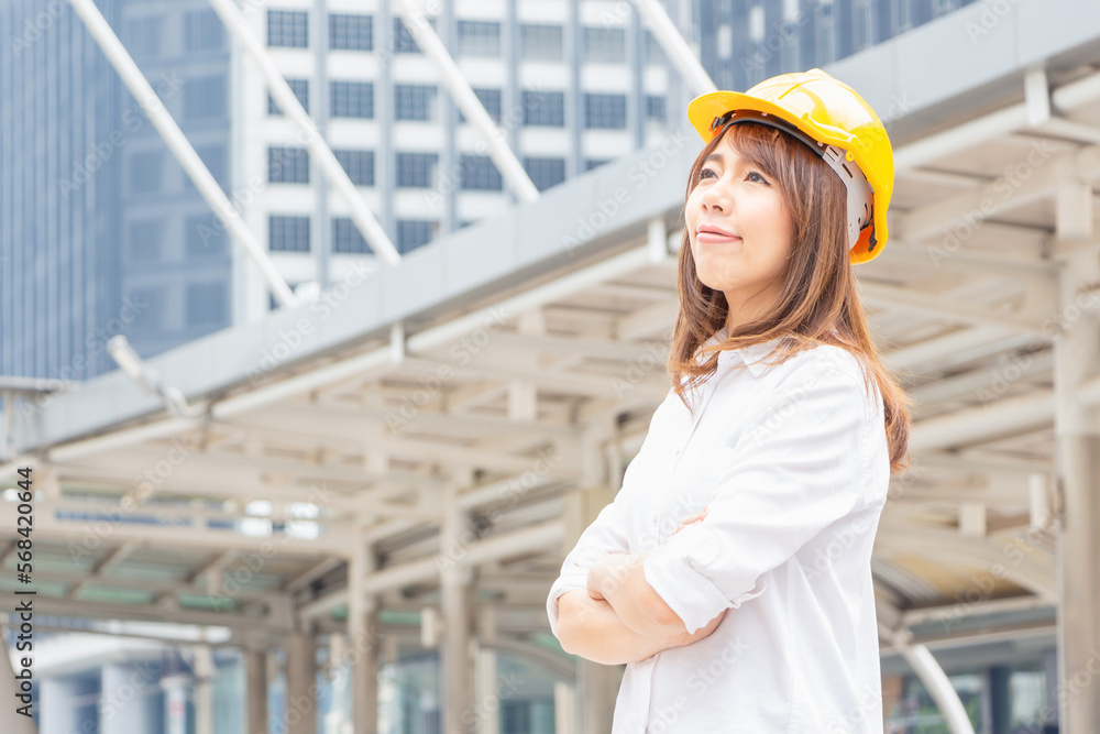Young architect woman in yellow helmet standing at the city, Female engineer at building construction site Young architect woman in yellow helmet standing at the city, Female engineer at building construction site