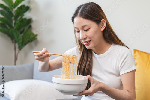young woman eating instant noodles at home.