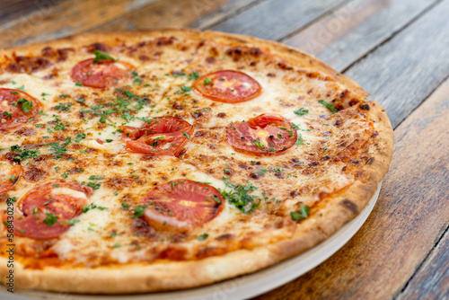 Margherita pizza or Margarita pizza on wooden background. Close up homemade fresh Italian Margherita or Margarita pizza with cheese, gourmet, basil. Pizza is traditional food for Italian on Italy.