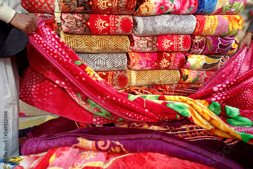 A vendor displaying colorful blankets at a makeshift roadside stall