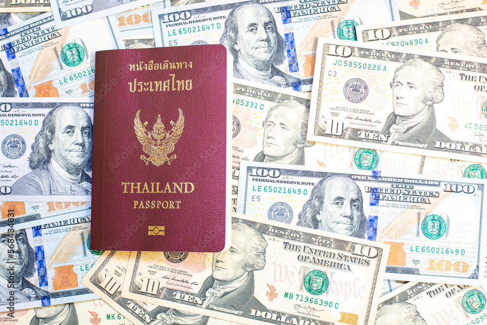 Passport of Thailand on group of money dollars banknotes arranged. Passport on the dollars banknotes chaotic manner. .Exchange money, money, cash, finances,Travel and immigration concept. Passport of Thailand on group of money dollars banknotes arranged. Passport on the dollars banknotes chaotic manner. .Exchange money, money, cash, finances,Travel and immigration concept.
