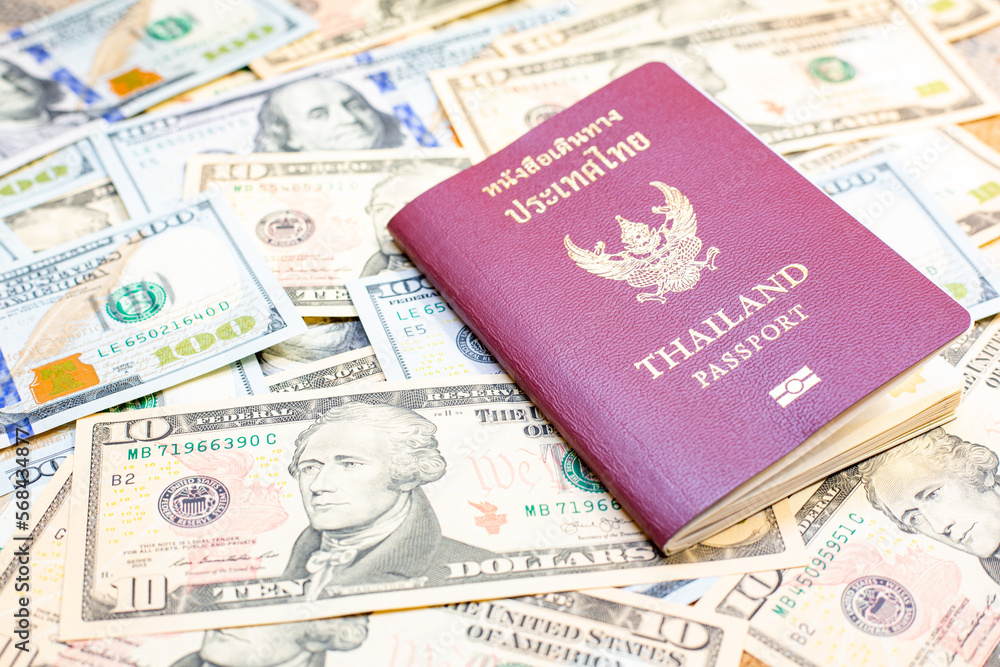 Passport of Thailand on group of money dollars banknotes arranged. Passport on the dollars banknotes chaotic manner. .Exchange money, money, cash, finances,Travel and immigration concept. Passport of Thailand on group of money dollars banknotes arranged. Passport on the dollars banknotes chaotic manner. .Exchange money, money, cash, finances,Travel and immigration concept.