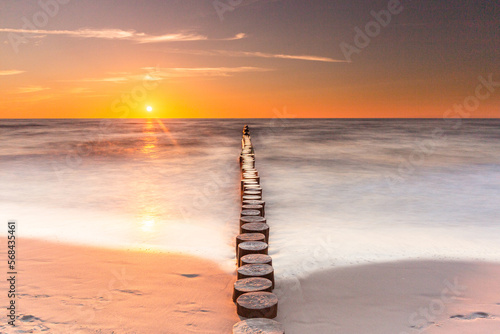 Colorful sunset on the Baltic Sea in Rowy, Poland. Landscape with waterbreak in the sea under the sky at sunset.