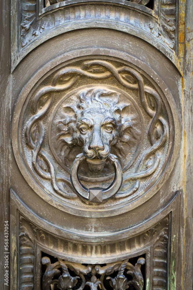 Antique decorative handle knocker on wooden vintage house door. Classical metal bronze lion head 