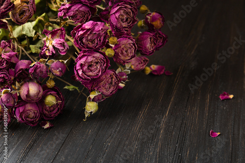Fototapeta Naklejka Na Ścianę i Meble -  Bouquet of dry roses close-up on a wooden background.