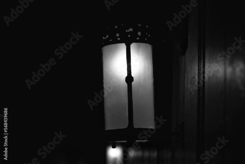 Vintage wall sconce shining in the darkness in black and white.