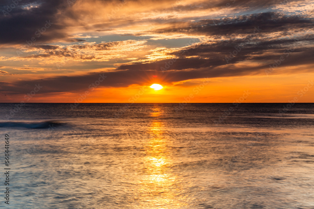 Fototapeta premium Colorful sunset on the Baltic Sea in Rowy, Poland. Landscape with waterbreak in the sea under the sky at sunset.