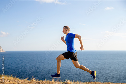 man athlete runner running trail in background blue sky and sea