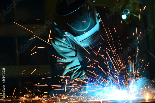 Workers wearing industrial uniforms and Welded Iron Mask at Steel welding plants, industrial safety first	