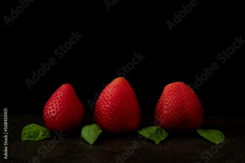 Close up image of raw strawberries on black background.
