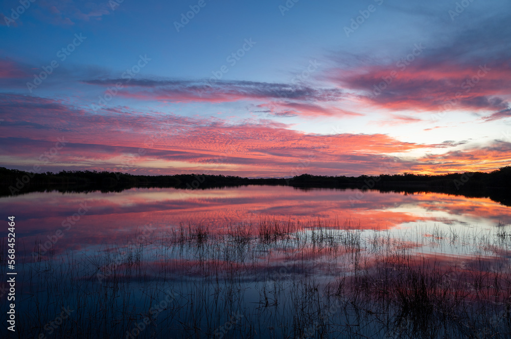 Colorful sunrise cloudscape reflected in calm water of Nine Mile Pond in Everglades National Park, Florida.