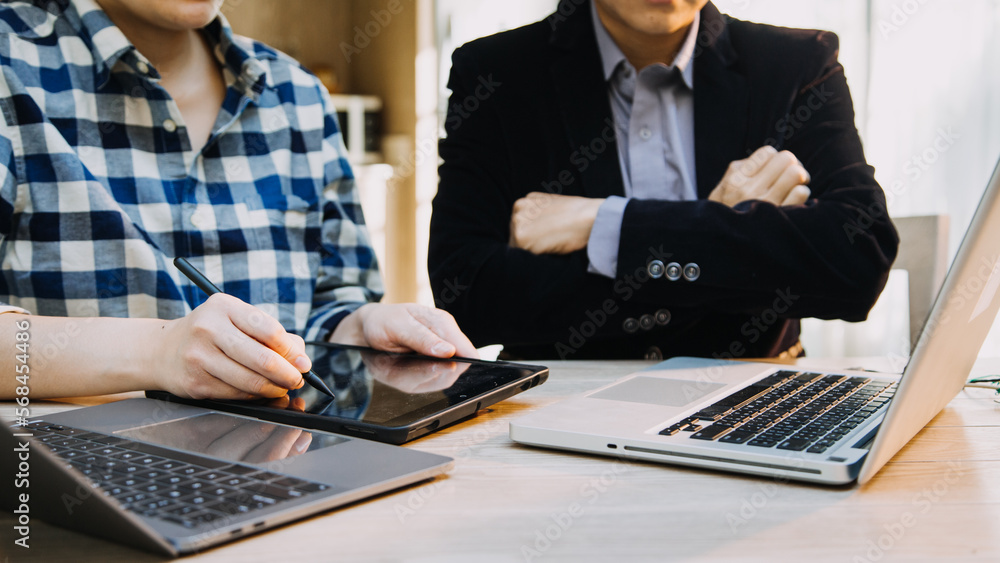 Mature businessman using a digital tablet to discuss information with a younger colleague in a modern business lounge