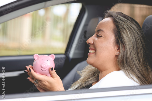 Uma mulher muito feliz segurando um cofrinho estando dentro de um carro. photo