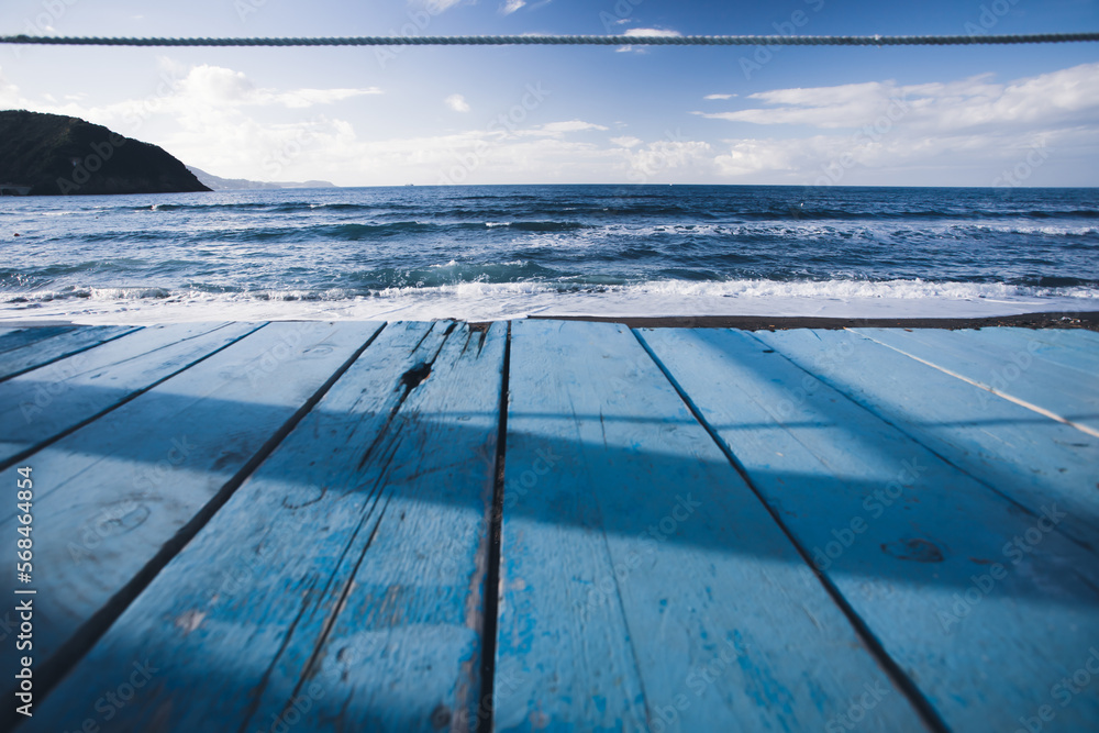 Wooden perspective on blue water shore and blue sky at coast