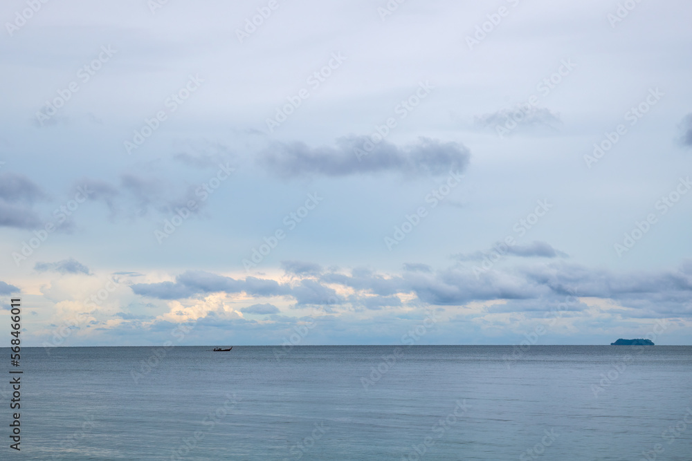 Blue tropical seascape with lone long tail boat and a distant island.
