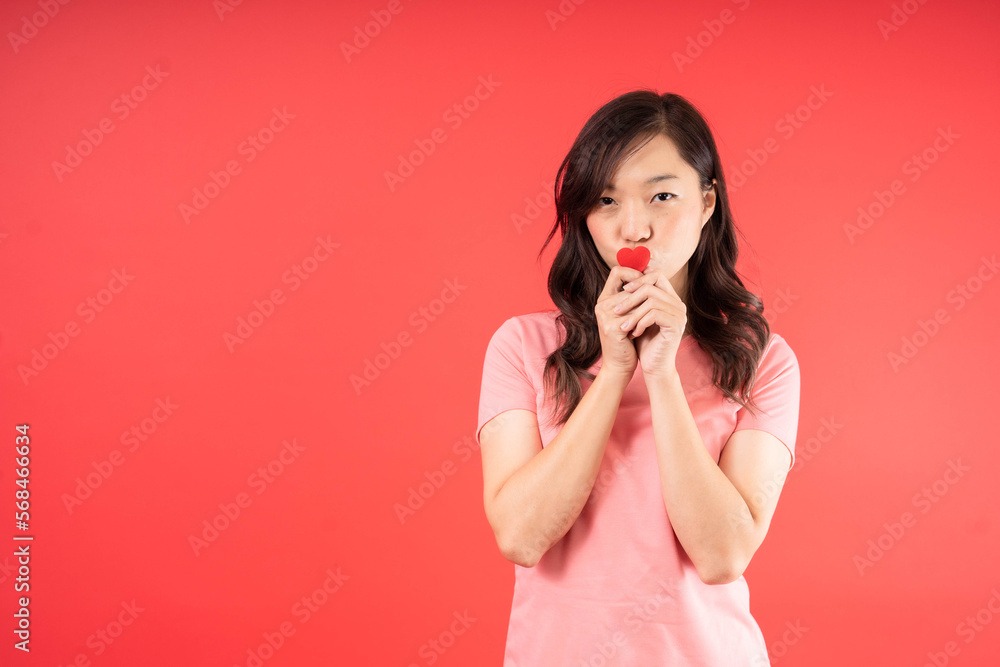 Happy beautiful Asian woman send kiss with small little heart isolated over red background. Valentines Day concept.