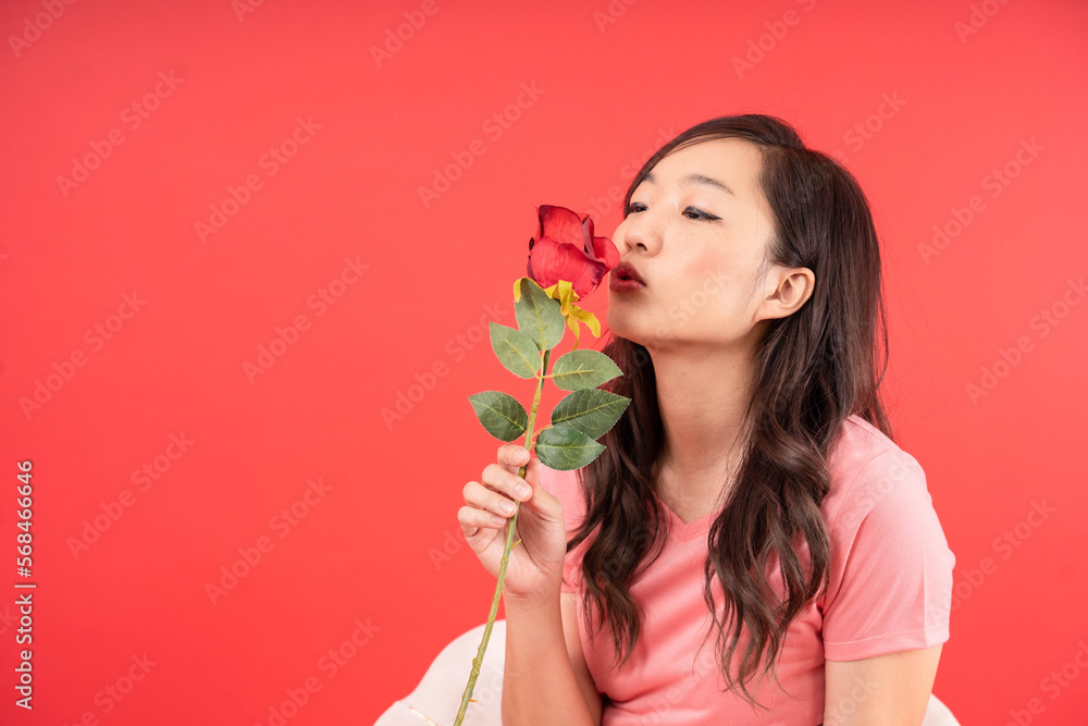 Happy beautiful Asian woman holding Rose Flower and kiss isolated over red background. Valentines Day concept. Happy beautiful Asian woman holding Rose Flower and kiss isolated over red background. Valentines Day concept.