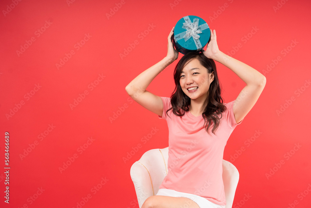 Happy beautiful Asian woman holding gift box isolated over red background. Valentines Day concept. Emotion smile Happy beautiful Asian woman holding gift box isolated over red background. Valentines Day concept. Emotion smile