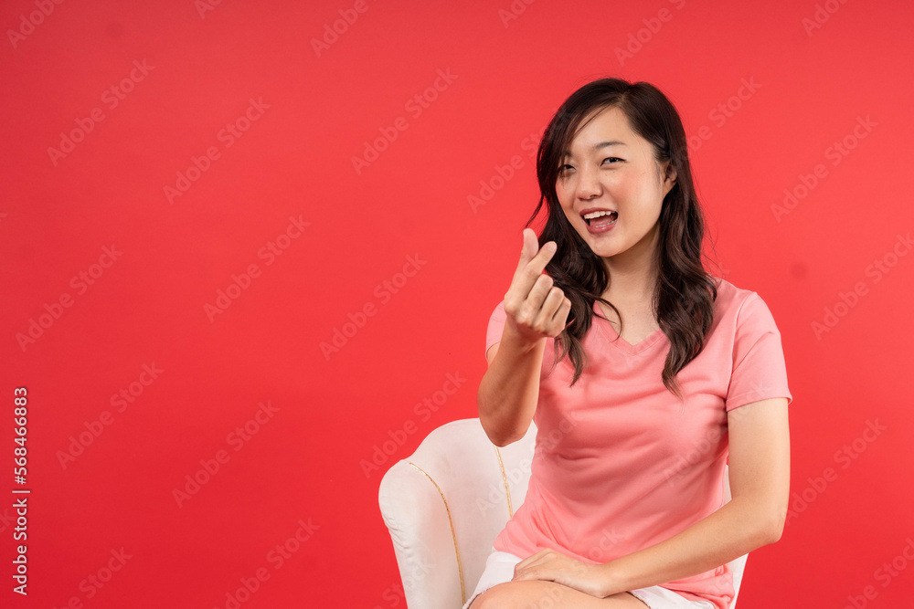 Happy beautiful Asian woman showing mini heart sign isolated on red background, Speading love and happiness concept Happy beautiful Asian woman showing mini heart sign isolated on red background, Speading love and happiness concept