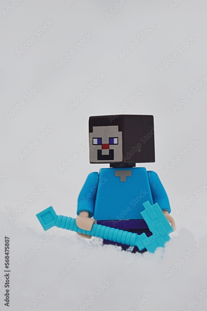 Obraz premium LEGO Minecraft figure of main character Steve standing with his diamond pickaxe in deep snow.