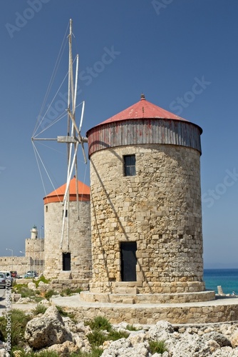 Stone windmills in clear weather in spring, Mandraki port of Rhodes, Greece.