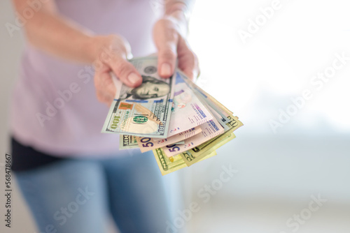 Close-up of woman's hands holding bills of 50 thousand Colombian pesos and 100 dollars
