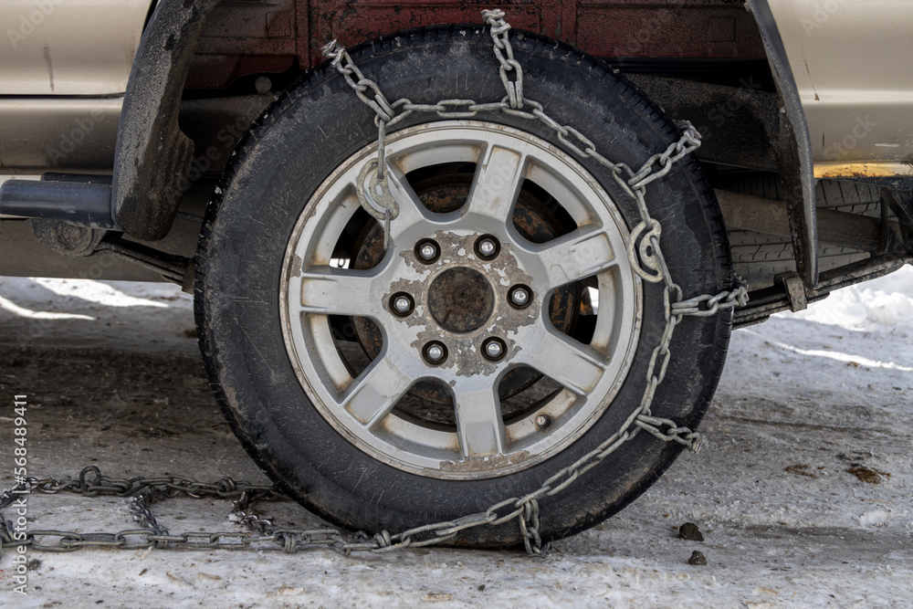 Wheel Car with winter chains for snow and ice road . Snow chains on tire. The wheel of a car with snow chain
