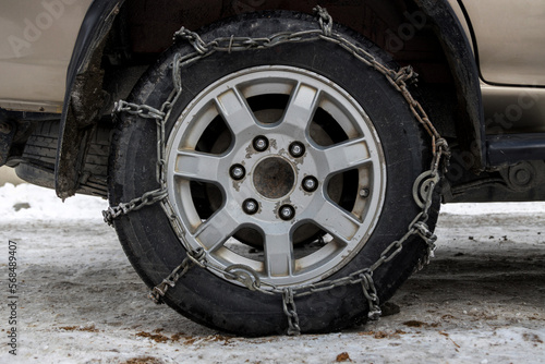 Wheel Car with winter chains for snow and ice road . Snow chains on tire. The wheel of a car with snow chain