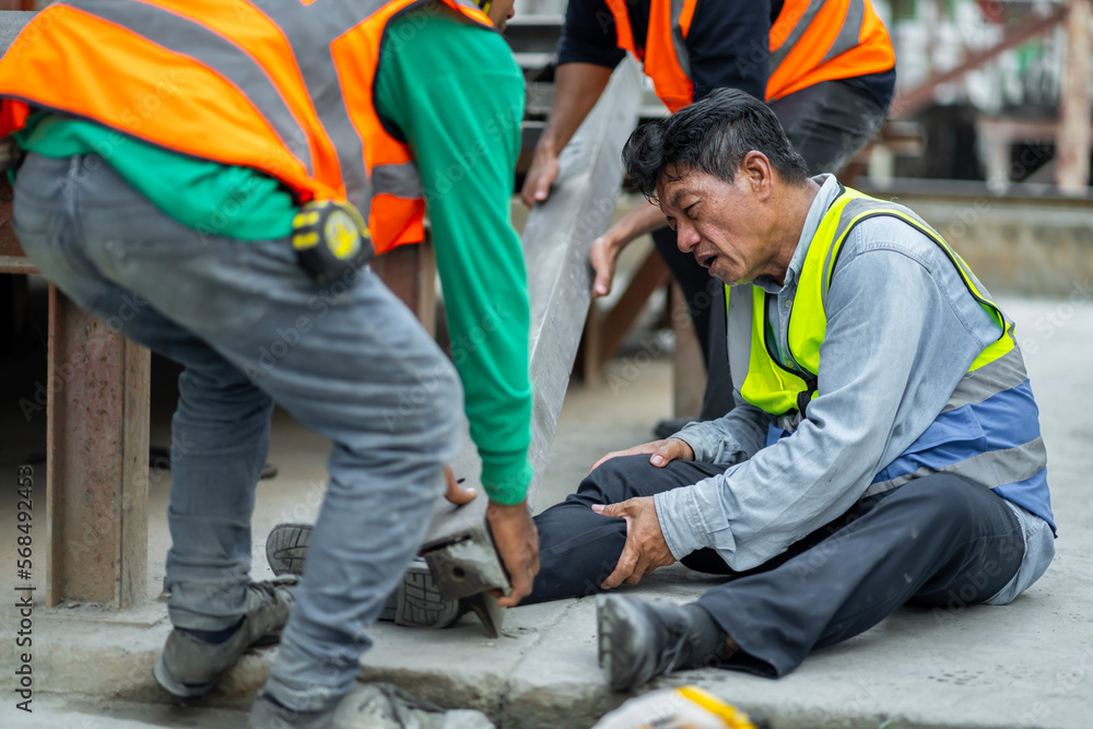 An engineer has an accident where steel falls on his leg at work, causing serious leg injuries. and get help from colleagues in the area under construction industrial factory, concept, safe work An engineer has an accident where steel falls on his leg at work, causing serious leg injuries. and get help from colleagues in the area under construction industrial factory, concept, safe work