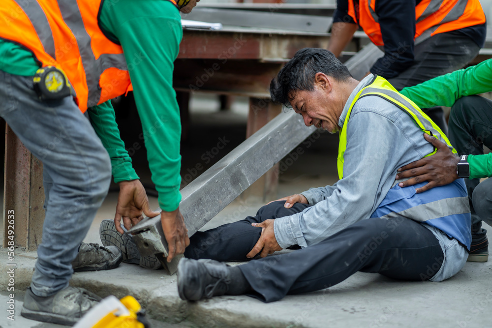 An engineer has an accident where steel falls on his leg at work, causing serious leg injuries. and get help from colleagues in the area under construction industrial factory, concept, safe work An engineer has an accident where steel falls on his leg at work, causing serious leg injuries. and get help from colleagues in the area under construction industrial factory, concept, safe work