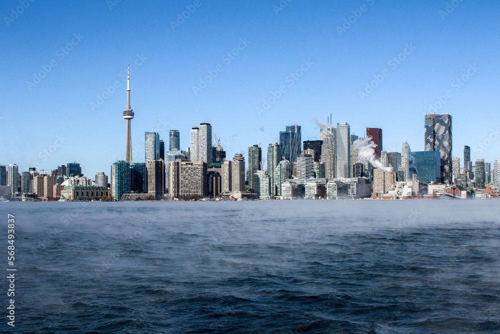 Cold frozen steaming lake with Toronto skyline in winter
