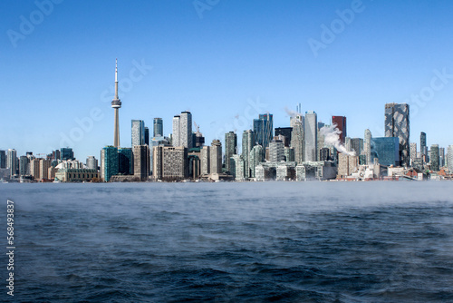 Cold frozen steaming lake with Toronto skyline in winter